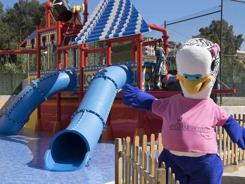 Maskotka ptaka przed niebieską zjeżdżalnią wodną w parku wodnym.