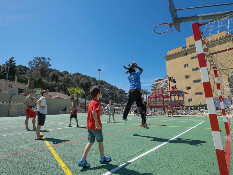 Dzieci grają w koszykówkę na zewnątrz przy czystym niebie.