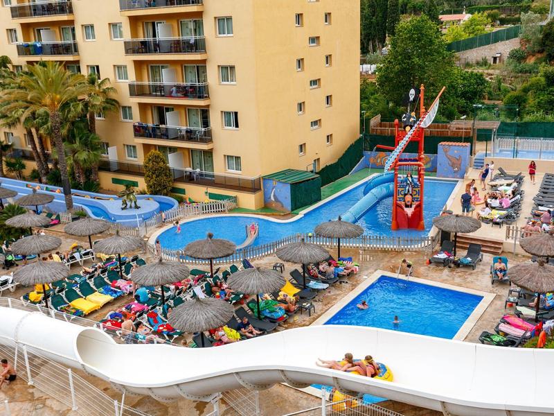 Tętniący życiem basen zewnętrzny z zjeżdżalnią i leżakami w hotelu.