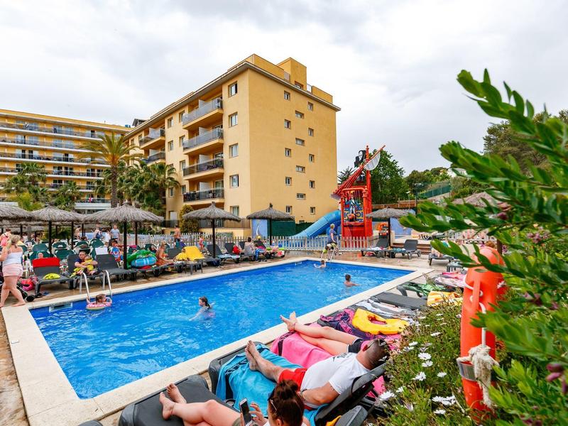 Tętniący życiem basen hotelowy z leżakami, kolorową zjeżdżalnią i gośćmi na zewnątrz.