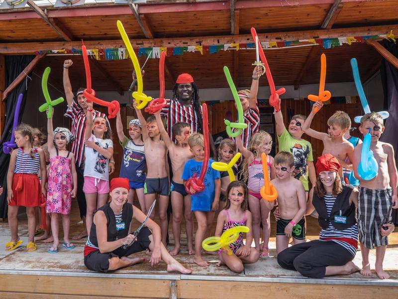 Dzieci z kolorowymi balonami i animatorzy przebrani na zewnątrz na scenie