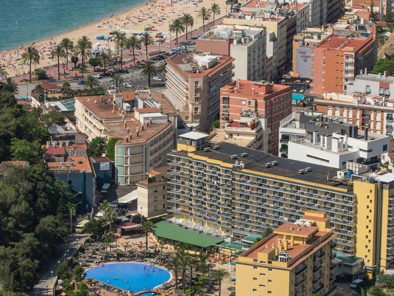 Miasto nad morzem z plażą, hotelami i okrągłym niebieskim basenem.