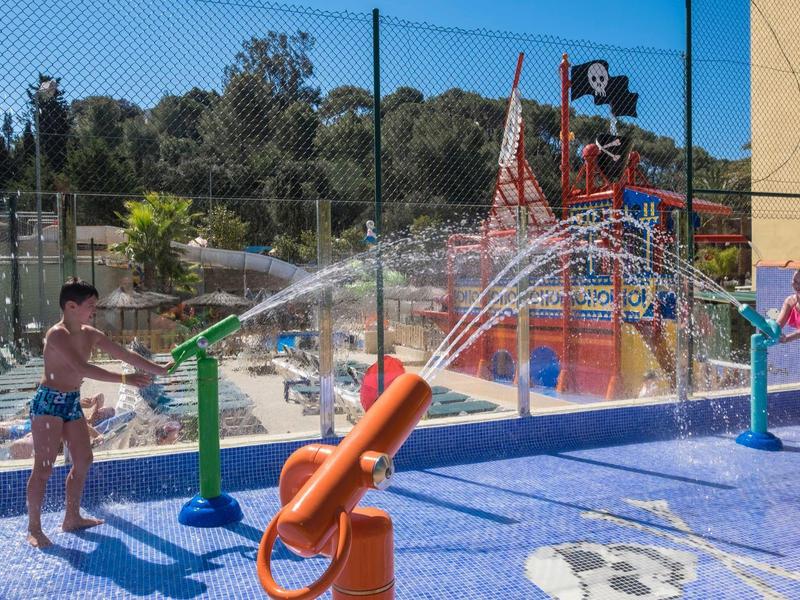 Dzieci bawiące się działkami wodnymi na zewnątrz w parku wodnym przy słonecznej pogodzie.