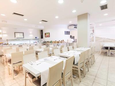 Salle à manger moderne et lumineuse avec tables et chaises blanches dans un hôtel.