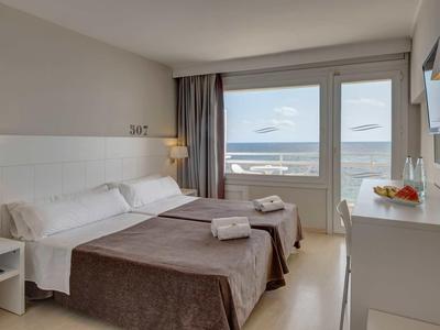 Chambre d'hôtel lumineuse avec lit double, vue sur la mer et mobilier moderne.