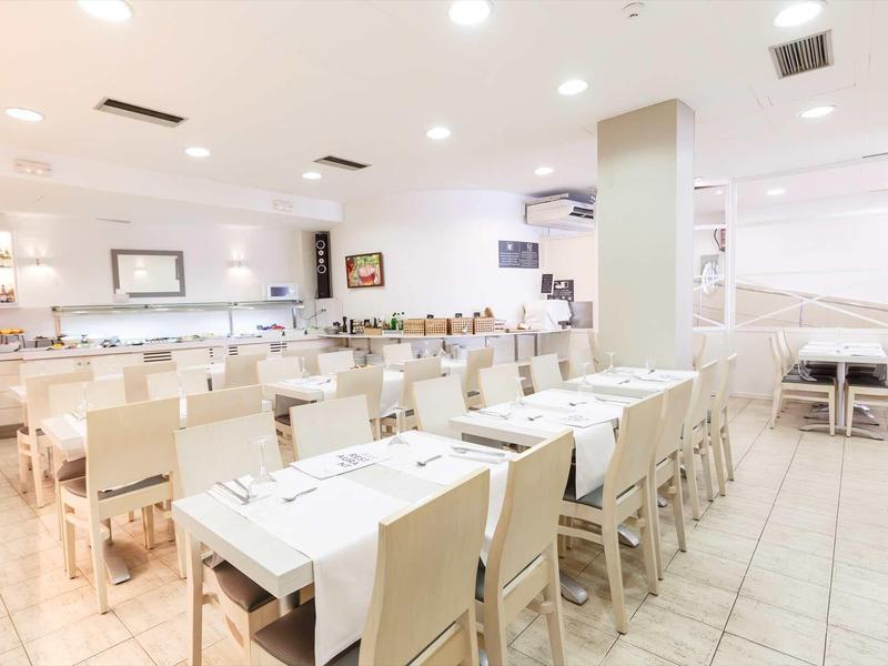 Salle à manger moderne et lumineuse avec tables et chaises blanches dans un hôtel.
