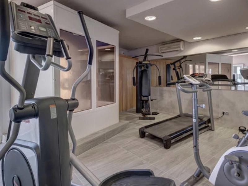 Salle de sport moderne avec tapis roulant, vélo elliptique et vue sur la mer.