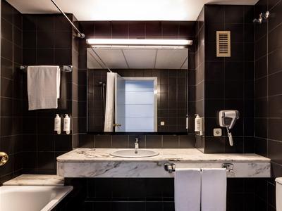 Modern bathroom with dark tiles, large mirror, and white sink.