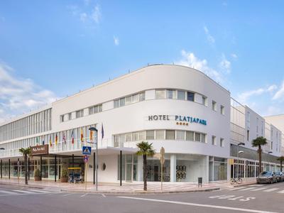 Modern white hotel building with clean lines at a street corner during daylight.