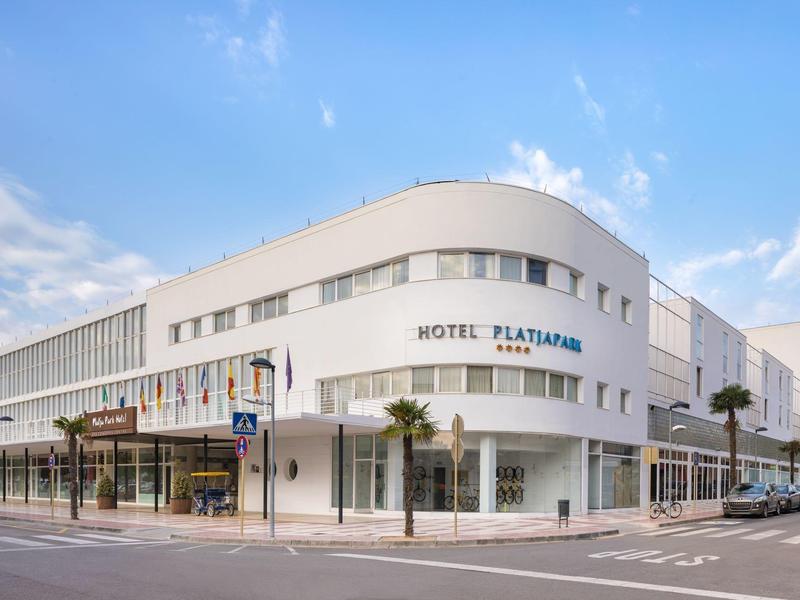 Modern white hotel building with clean lines at a street corner during daylight.