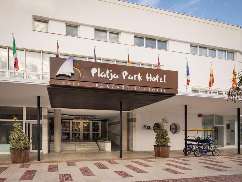 Entrance of Platja Park Hotel with white facade and brown sign.