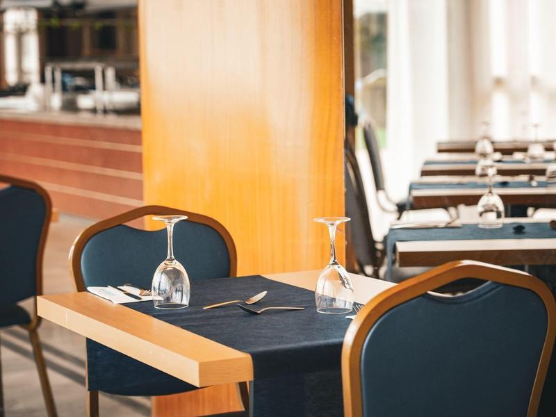 Elegant restaurant with set tables and upside-down wine glasses on black tablecloths.