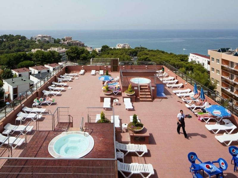Large rooftop terrace with sunbeds, hot tubs, and sea view.