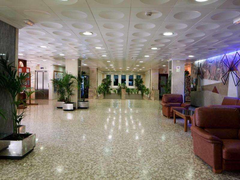 Spacious, well-lit hotel lobby area with seating and plants.