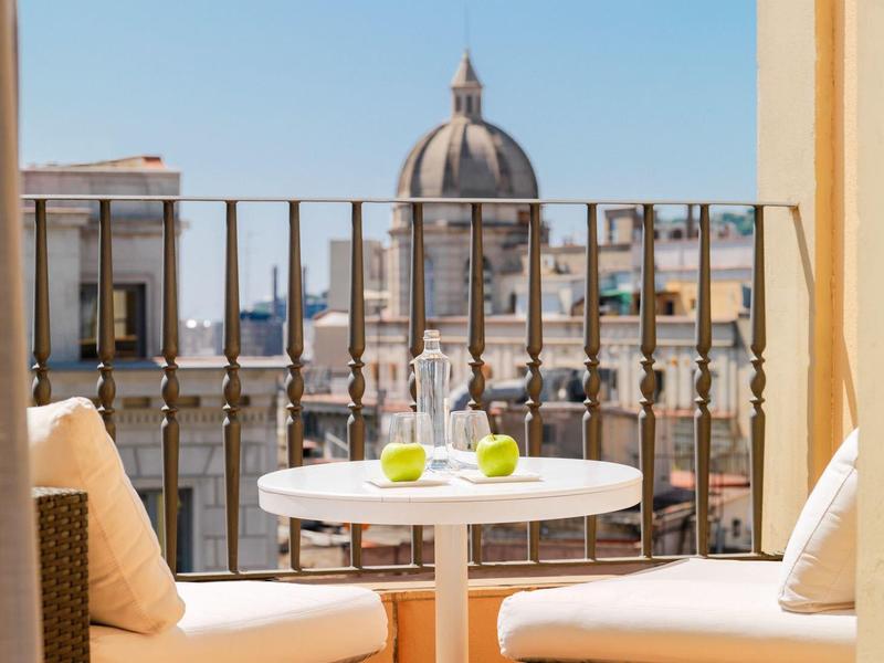 Accogliente balcone con tavolo rotondo, cuscini e vista sulla cupola della città sotto un cielo limpido.