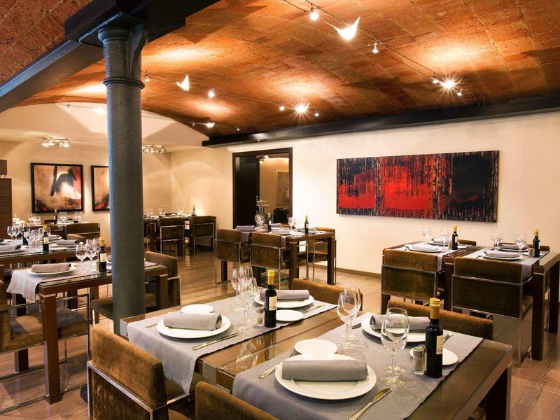 Interno accogliente di ristorante con tavoli in legno apparecchiati e illuminazione calda.