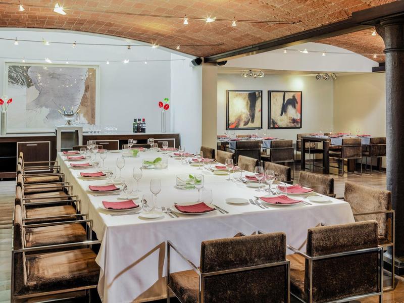 Sala da pranzo elegante con grande tavolo apparecchiato, sedie in legno e opere d'arte alle pareti.