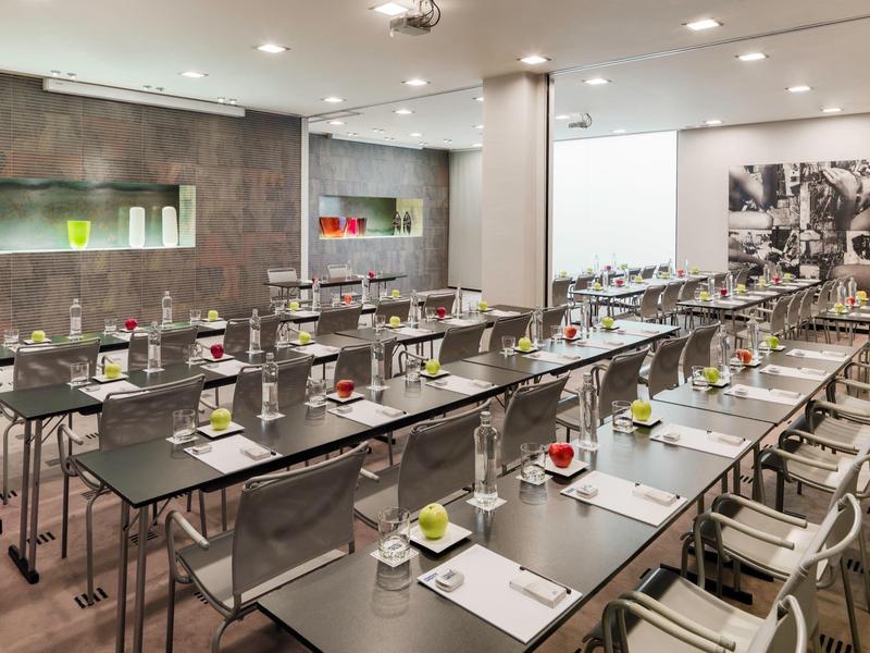 Sala conferenze moderna con tavoli, sedie e quaderni pronti per una riunione.