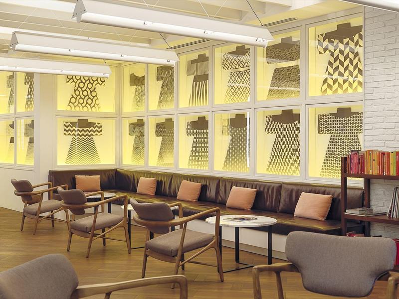 Area lounge moderna con scaffali a parete decorati, sedute imbottite e sedie in legno.