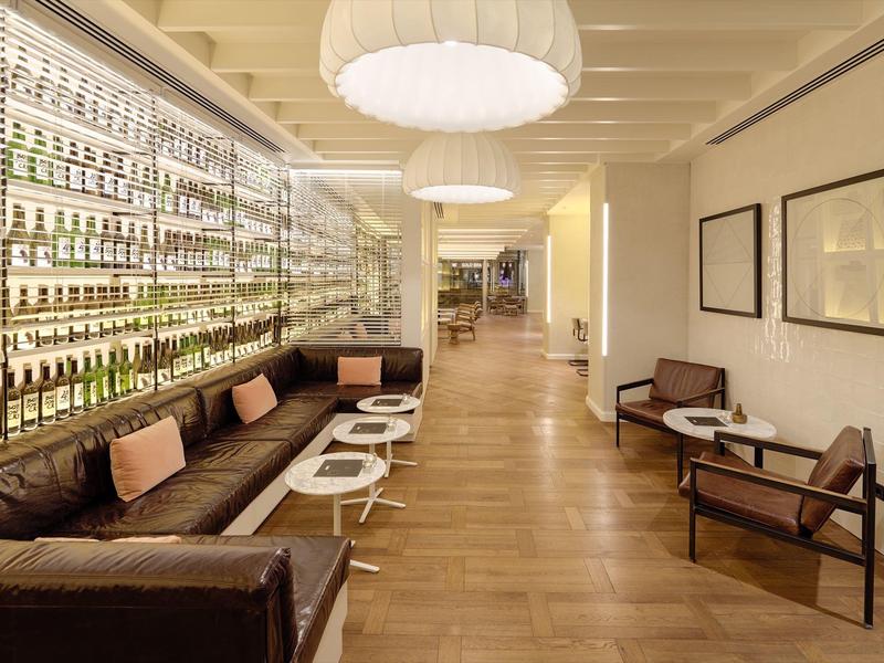 Lounge moderno con divani in pelle, scaffali di bottiglie di vetro e pavimento in legno.