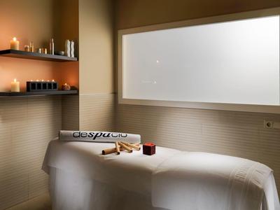 Sala de masajes tranquila con camilla acogedora y luz de velas relajante.