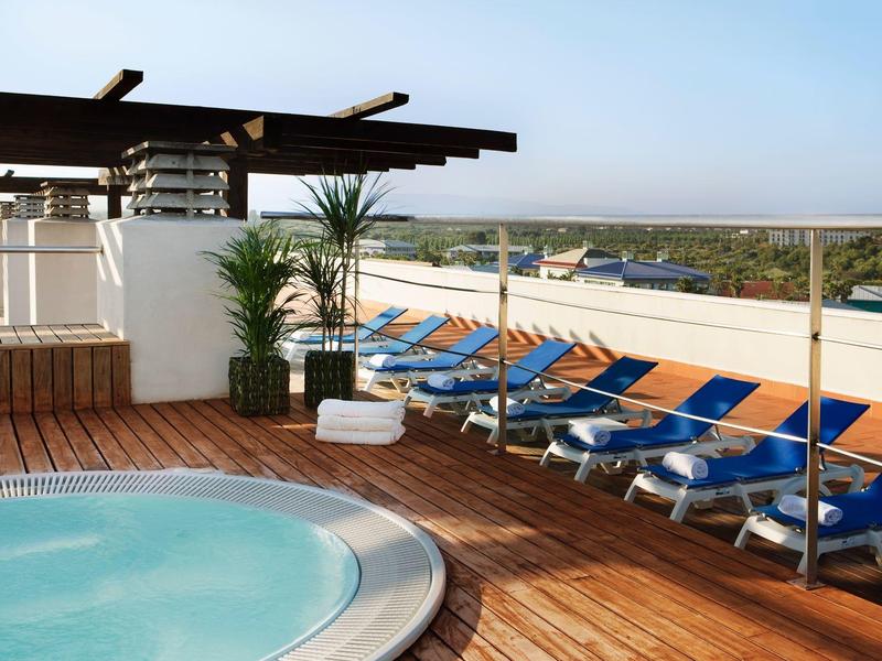 Terraza con piscina redonda y varias tumbonas azules para relajarse bajo el sol