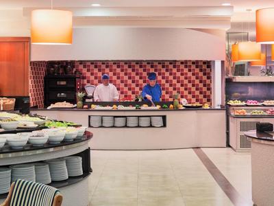 Moderne hotelbuffet met koks die eten bereiden achter de toonbank en diverse gerechten in het zicht.