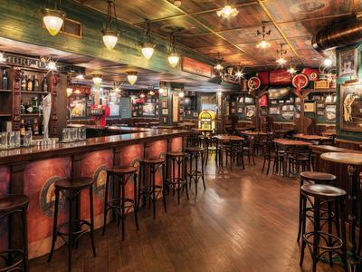 Gezellige bar met houten krukken, een lange toog en warme verlichting.