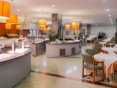 Lichte, moderne hotel eetruimte met ronde buffetstations en netjes gedekte tafels.