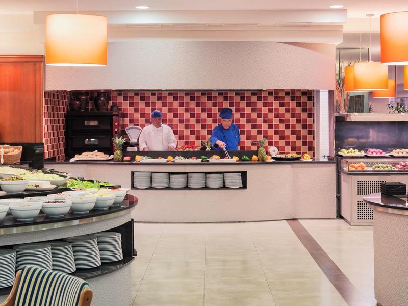 Moderne hotelbuffet met koks die eten bereiden achter de toonbank en diverse gerechten in het zicht.