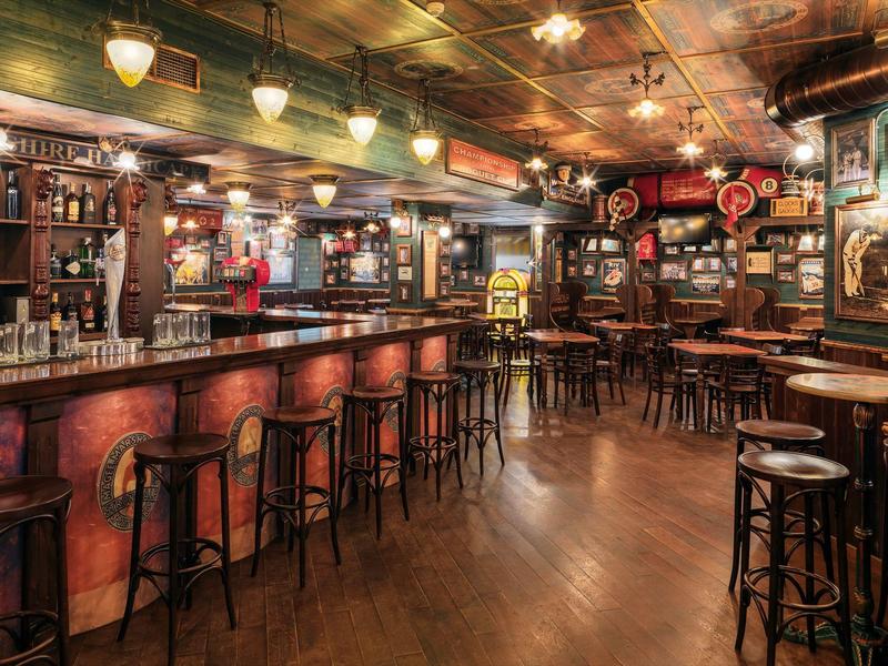 Gezellige bar met houten krukken, een lange toog en warme verlichting.