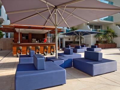Terrasse d'hôtel avec canapés bleus et grands parasols pour détente en plein air.