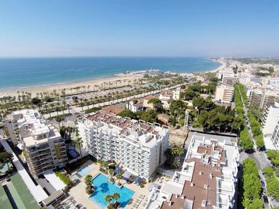 Vue aérienne d'un hôtel avec piscine sur la côte et vue large sur la mer.
