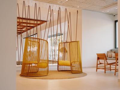 Deux fauteuils suspendus jaunes modernes dans une chambre d'hôtel lumineuse et minimaliste.