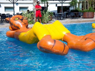 Piscine avec un grand radeau gonflable en forme de chat orange.