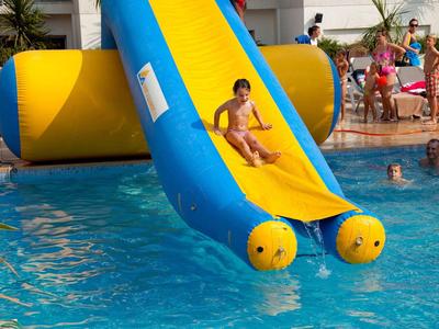 Enfant glissant sur un toboggan gonflable dans une piscine animée.