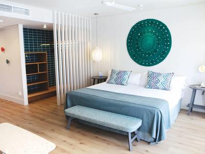 Chambre d'hôtel moderne avec lit, banc, lampe et décoration murale verte.