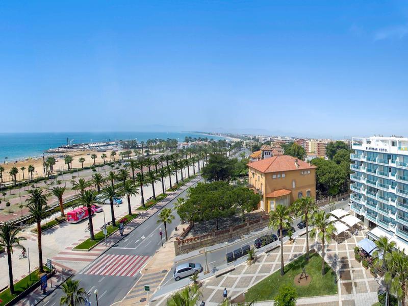 Vue d'une route côtière bordée de palmiers et de bâtiments modernes sous un ciel dégagé.