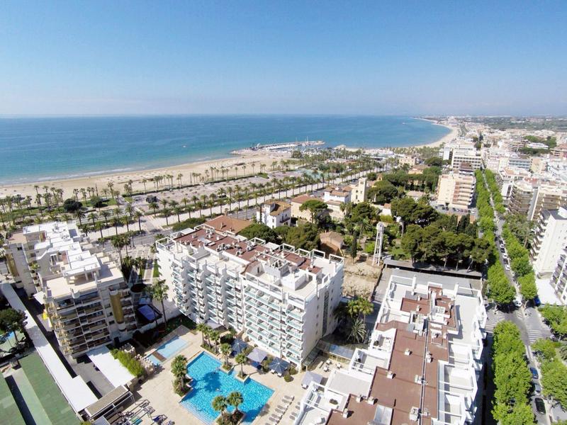 Vue aérienne d'un hôtel avec piscine sur la côte et vue large sur la mer.