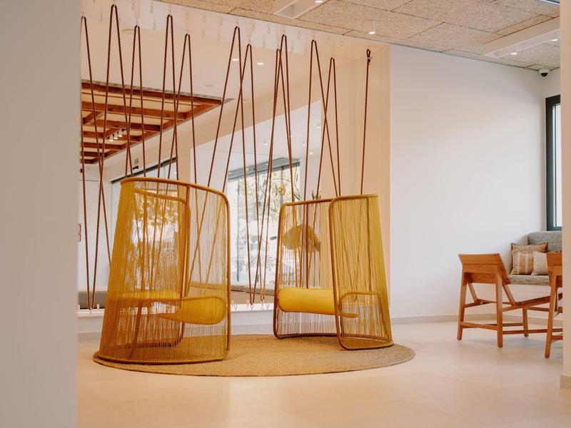 Deux fauteuils suspendus jaunes modernes dans une chambre d'hôtel lumineuse et minimaliste.