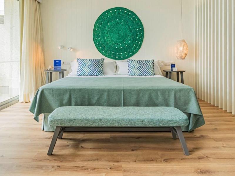 Chambre d'hôtel moderne avec grand lit, décoration murale verte et sol en bois