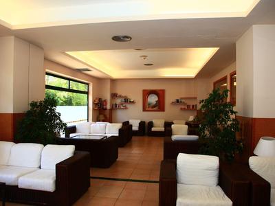 Bright hotel lounge with white sofas, potted plants, and wall art under soft ceiling lights