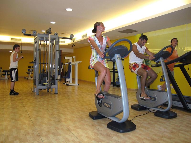 People exercising on gym machines in a hotel fitness center.