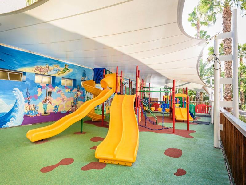 Piscina moderna del hotel con tumbonas y vista al mar azul bajo cielo despejado.