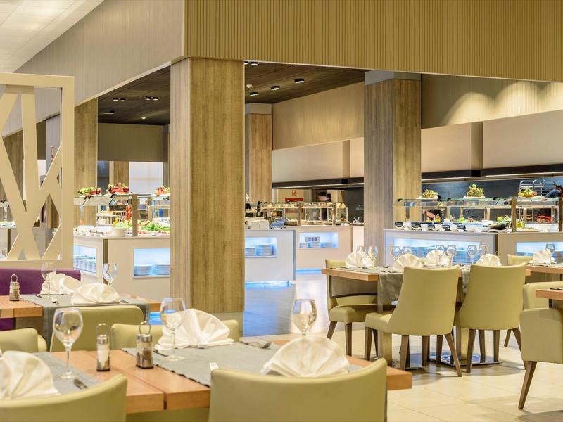 Interior elegante de restaurante con mesas puestas y sillas cómodas en tonos cálidos.