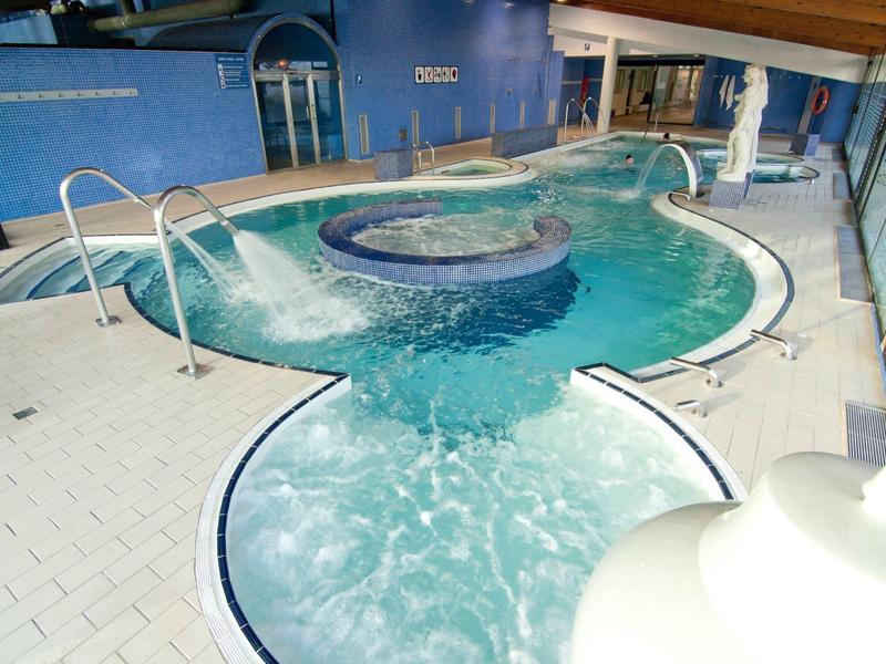 Jacuzzi moderno y claro con área de asientos integrada junto a una piscina cubierta.