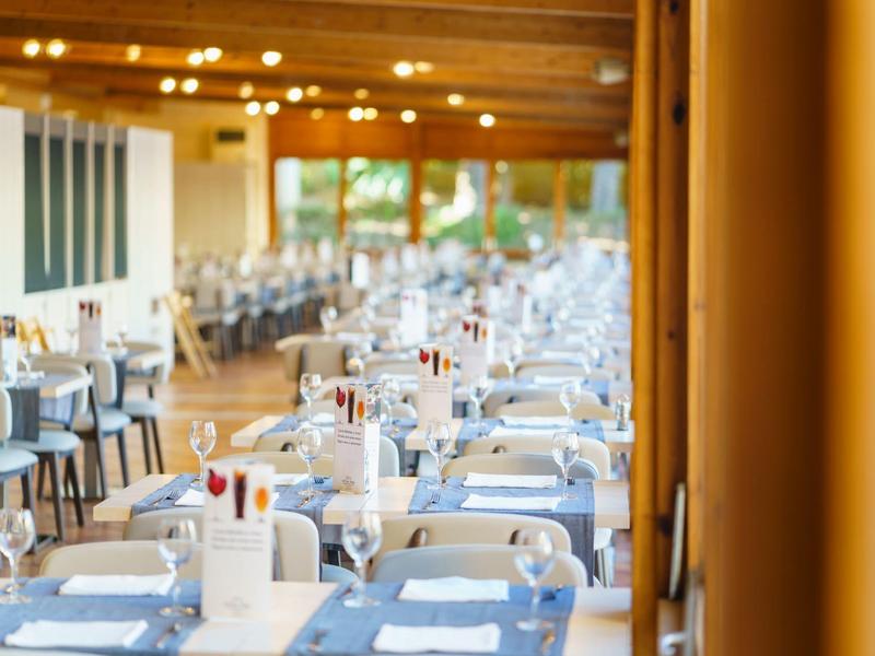 Restaurante elegante con manteles blancos y vista a grandes ventanas, ambiente acogedor.