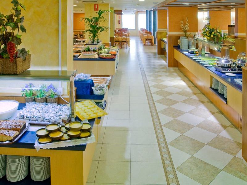 Area buffet in un ristorante luminoso decorata con vari piatti e piante.