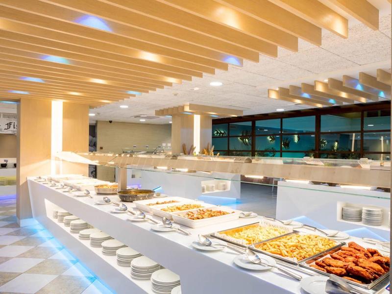 Buffet moderno con una varietà di piatti caldi in un'area pranzo luminosa e spaziosa.
