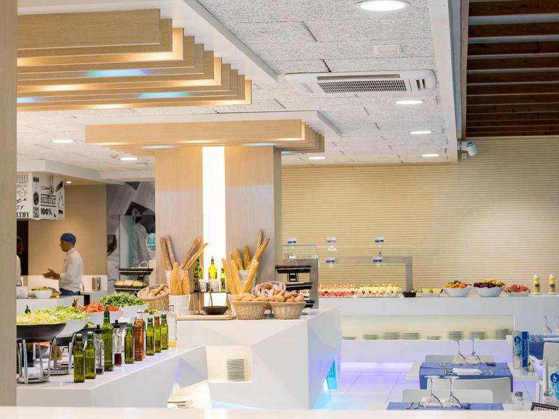 Buffet moderno dell'hotel con varie bottiglie di olio d'oliva e ingredienti freschi in un ambiente luminoso.